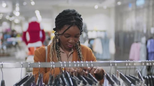 Woman Browsing Clothes Rack in Clothing Store