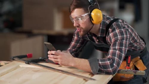 handsome man in work uniform takes pictures on the phone wooden products