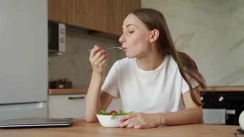 Woman enjoys healthy salad in modern kitchen