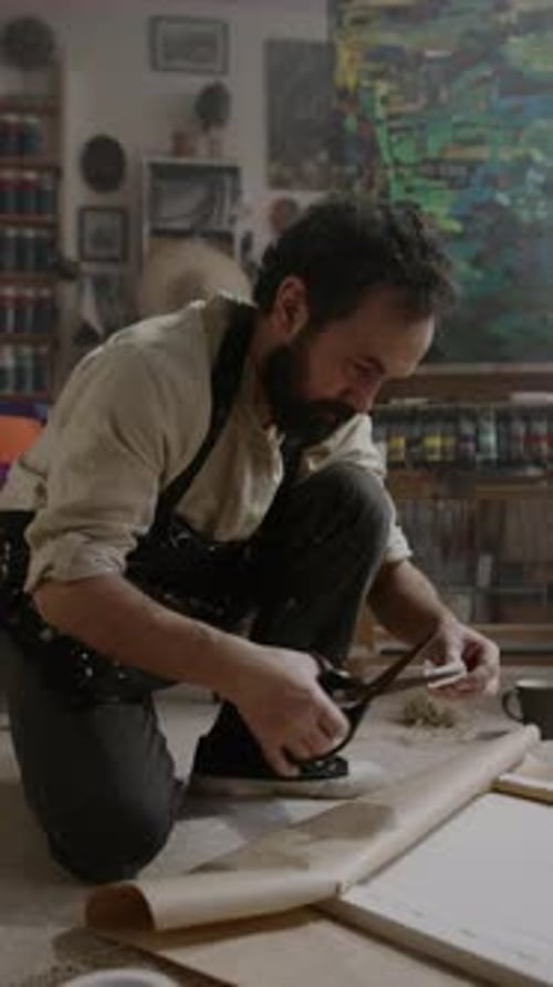 Male Artist Wrapping Painting in Craft Paper Using Adhesive Tape