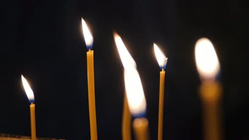 Burning Church Candles By the Dark Background