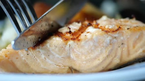 Enjoying a Delicious Piece of Salmon with a Side of Vegetables at a Cozy Restaurant