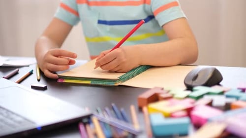 Child writing in notebook at table