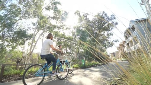 Couple biking through green park on sunny summer day tracking shot