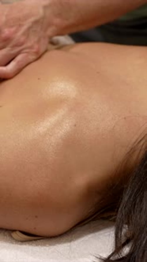 Massage Therapist Massages Woman's Back Indoors Close Up