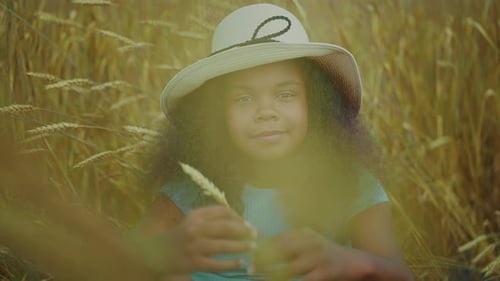 Young Girl Enjoys Summer in a Wheat Field Wearing a Sun Hat