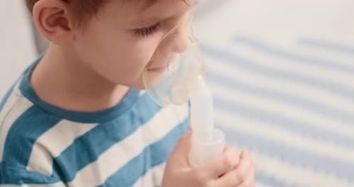 Young Boy Uses Nebulizer Mask Indoors