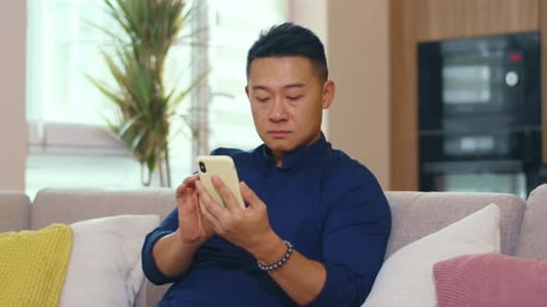 Young Adult Using Smartphone on Couch at Home