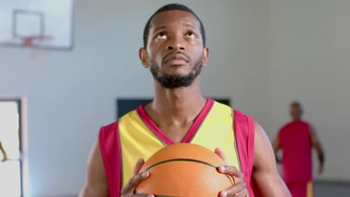African American man holds a basketball in a gym