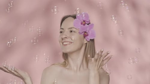 Tender Beautiful Woman with Naked Shoulders in the Studio on a Pink Background A Woman with Orchid