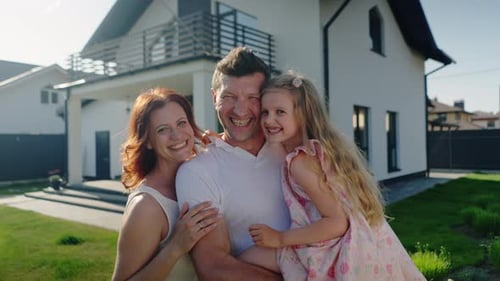 Happy Family Embracing in Front of House