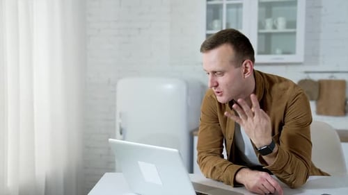 Enthusiastic Man Video Calling on Laptop at Home