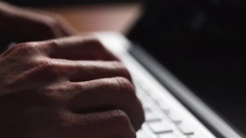 Young Man Works Typing on a Laptop Keyboard Closeup