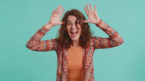 Playful Woman Makes Faces on Blue Background