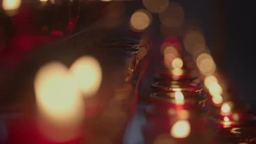 Red Glass Candles Lit in Rows at Night