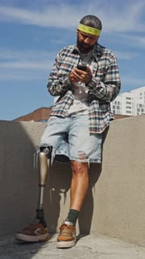 Man with Prosthetic Leg Using Smartphone Outdoors in Urban Area
