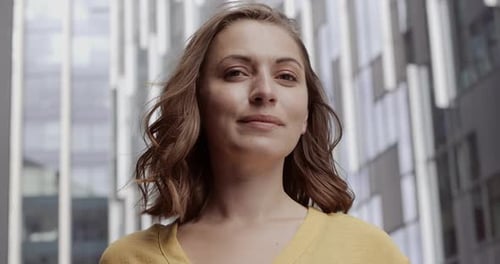 Portrait of pretty female smiling and looking to camera on city street