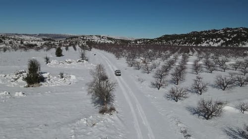 Van Driving Through Snowy Rural Landscape From Above