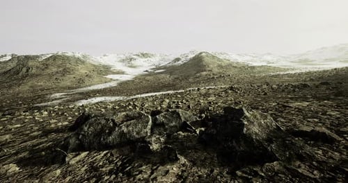 Vast Rocky Landscape with Snow Capped Mountains Under a Cloudy Sky