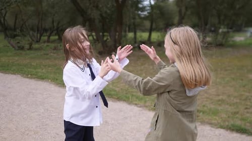Zwei kleine Mädchen klatschen zusammen in einem Sommerpark