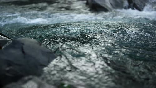 Powerful mountain river flowing in slow motion splashing over rocky rapids