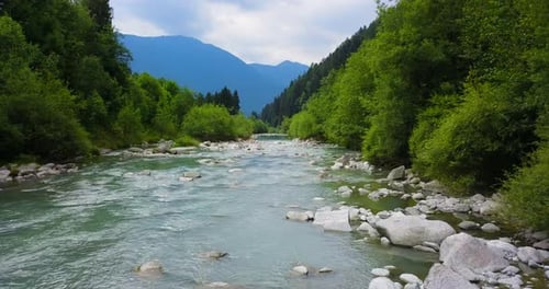 Aerial image of a lake surrounded by nature among trees and mountains.