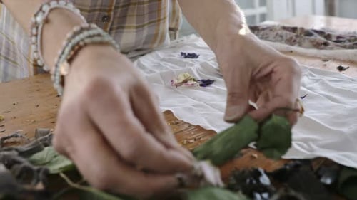 Woman Arranges Flower Petals on White Textile