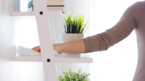 Woman wiping shelf with cloth at home