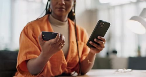 Woman Using Phone and Credit Card Indoors