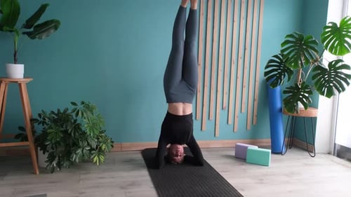 Jeune femme athlétique faisant la position debout ou en position de salamba sirsasana