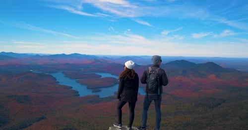 Couple hiking mountaintop overlooking lake placid park wilderness together