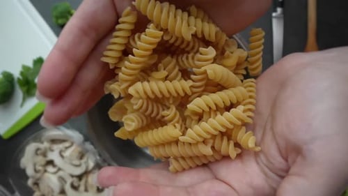 Hands Cooking Spiral Pasta in Boiling Water