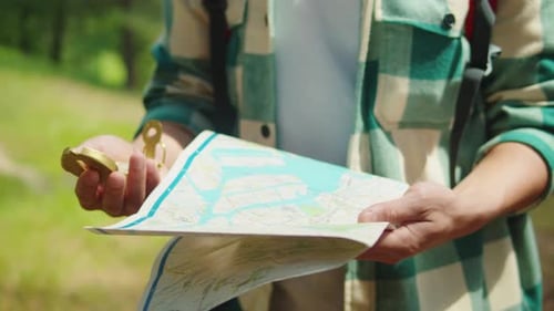 Person Holding Compass and Map in Woods