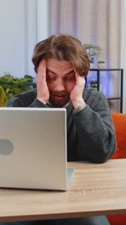 Frustrated Man Using Laptop at Table