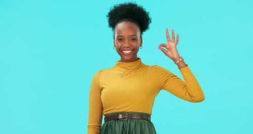 Okay, face and hands of happy woman in studio for vote, good review and news on blue background