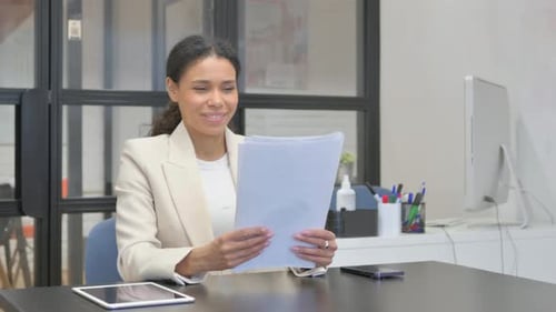 Professional Woman Smiling While Reviewing Documents in Office