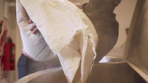 Homem trabalhando em uma cervejaria, colocando malte em uma panela de prata, Câmera lenta