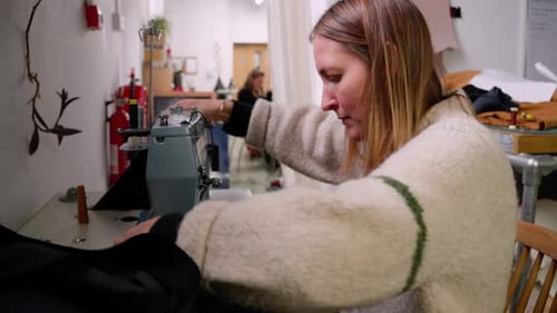 Wide shot of seamstress tailor sewing clothing with a sewing in a fashion design studio.