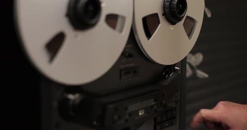 Man Hand Turns on Music on Reel to Reel Tape Recorder Playing Rotating Vintage Music Player Close Up