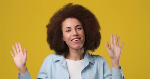 Young African American Woman with Afro Hair Having Fun Smiling and Dancing in Studio Against Orange