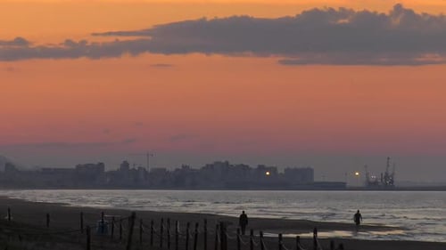 Menschen, die am Strand unter dem Abendhimmel spazieren gehen, Küstenlandschaft