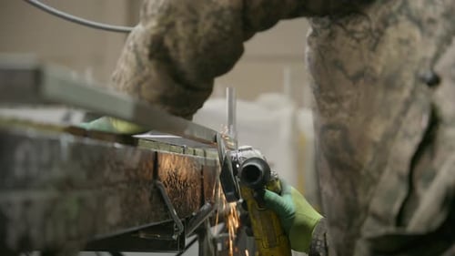 Industriearbeiter schleift Metall mit einem Winkelschleifer