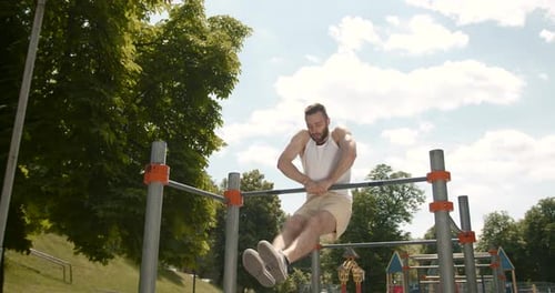 Young Man Doing Pull Ups on a Bar in the Park
