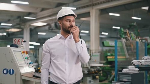 Talking by a walkie talkie. Man is working in the modern factory.