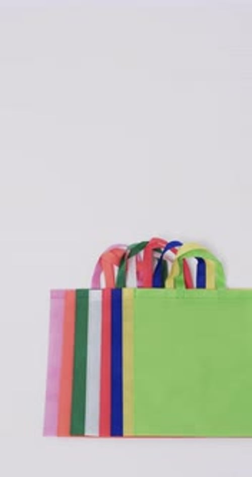Vertical video of multi coloured canvas bags with copy space on white background