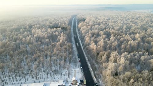 Vista aérea da paisagem de inverno com bosques cobertos de neve e estrada da floresta de asfalto preto no inverno frio