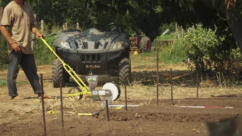 Barefoot farmer using a seeder in his private field, countryman working in the countryside