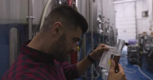 Le maître brasseur inspecte la qualité de la bière à l'aide de cuves de fermentation en acier inoxydable dans la brasserie