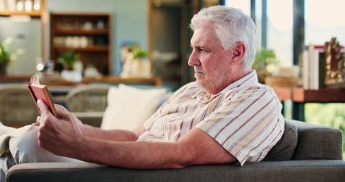Relaxed Senior Man Reading a Book on Sofa