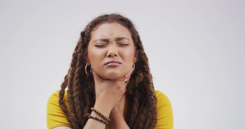 A young woman coughing against a grey background